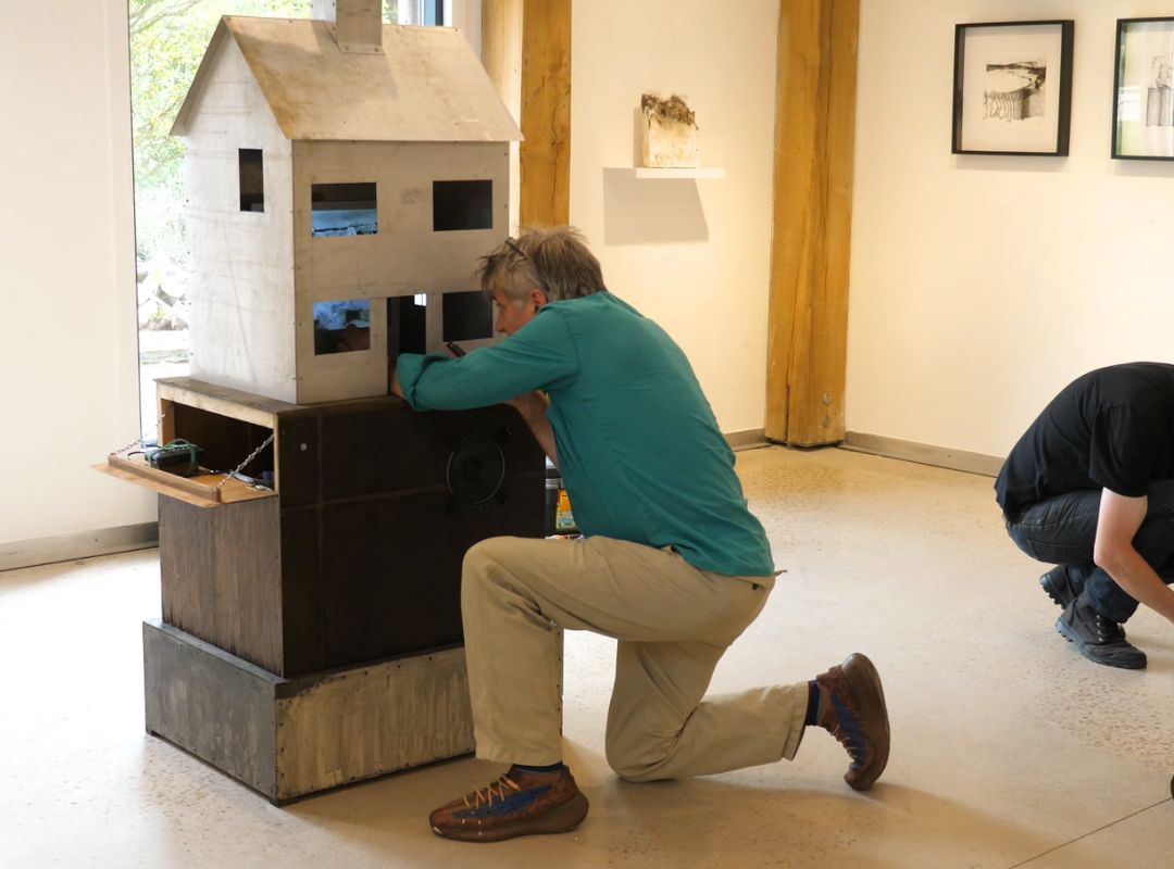 Tutor Jesse Leroy Smith helping with the installation of Ann Marie Whitton's house Artist Jesse Leroy Smith installing Ann Marie Whittons house sculpture with stop motion animation video inside
